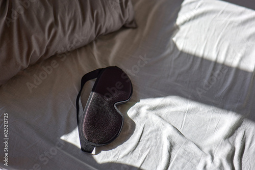 Morning light on empty bed with sleep mask