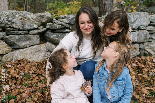 family portrait of smiling mother being hugged by her daughters