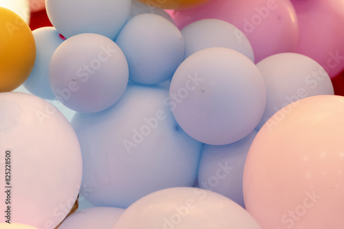 Photo zone with lots of yellow, blue, pink, purple balloons with golden color paper made butterflies. Beautiful pastel colored decor background for kids party, birthday celebration.
