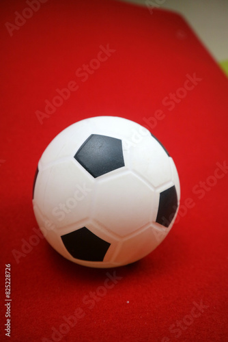 a small white and black toy rubber ball. Red background