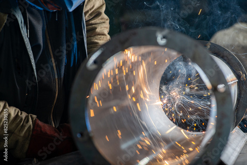 Male welder wearing a protective mask is welding stainless pipe photo