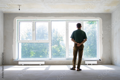unrecognizable millennial man in front of window in a new empty home