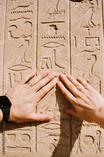Hands of a married couple over ancient Egyptian hieroglyphs photo