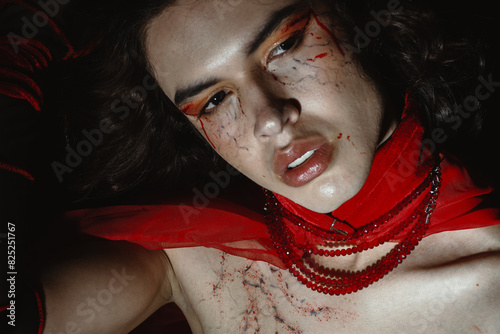 Dramatic portrait of a young queer man with a vampire make up  photo
