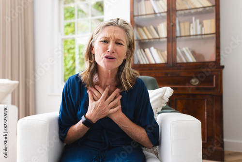 A caucasian senior female on video call at home, touching her chest