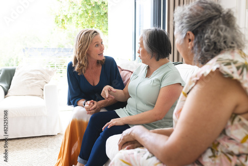 Diverse senior female friends chatting at home, wearing casual attire