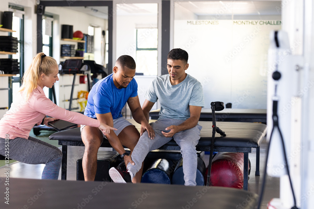 At rehabilitation center, diverse physical therapists helping biracial male patient