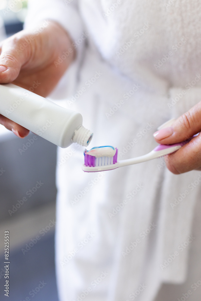 At home, mature Caucasian woman applying toothpaste on brush At home, mature Caucasian woman applying toothpaste on brush