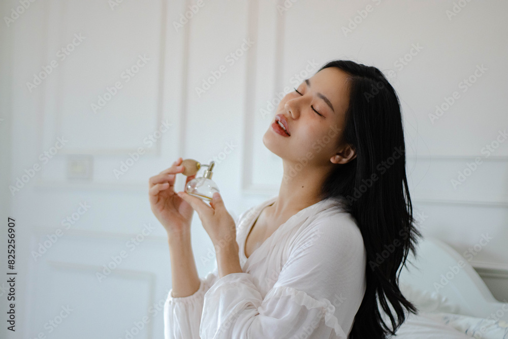 Young Asian woman applying perfume after waking up. Young Asian woman applying perfume after waking up.