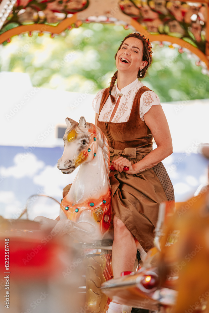 Obraz premium young woman with dirndl sits on the rocking horse on the carousel at the Oktoberfest/fair