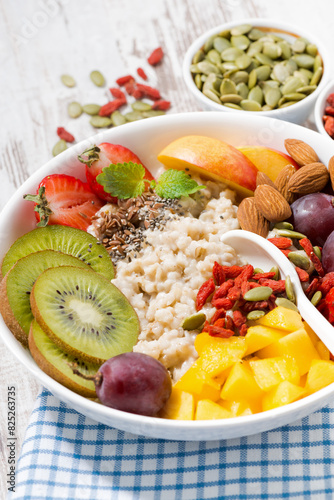 oatmeal porridge with fresh fruits and superfoods for breakfast, closeup