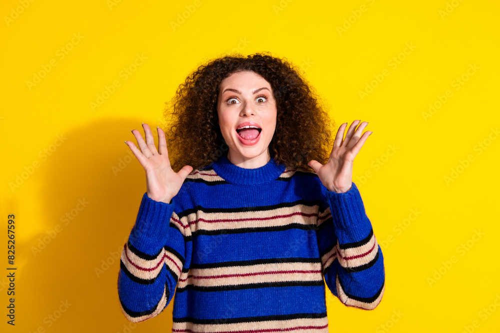 Portrait of overjoyed girl with wavy hair wear knit pullover astonished staring at sale raising palms isolated on yellow color background Portrait of overjoyed girl with wavy hair wear knit pullover astonished staring at sale raising palms isolated on yellow color background