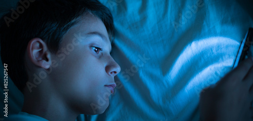 Billede på lærred Child with insomnia lying in bed looking at the cell phone at night