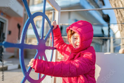 Bambina sorridente che gira un timone della nave photo