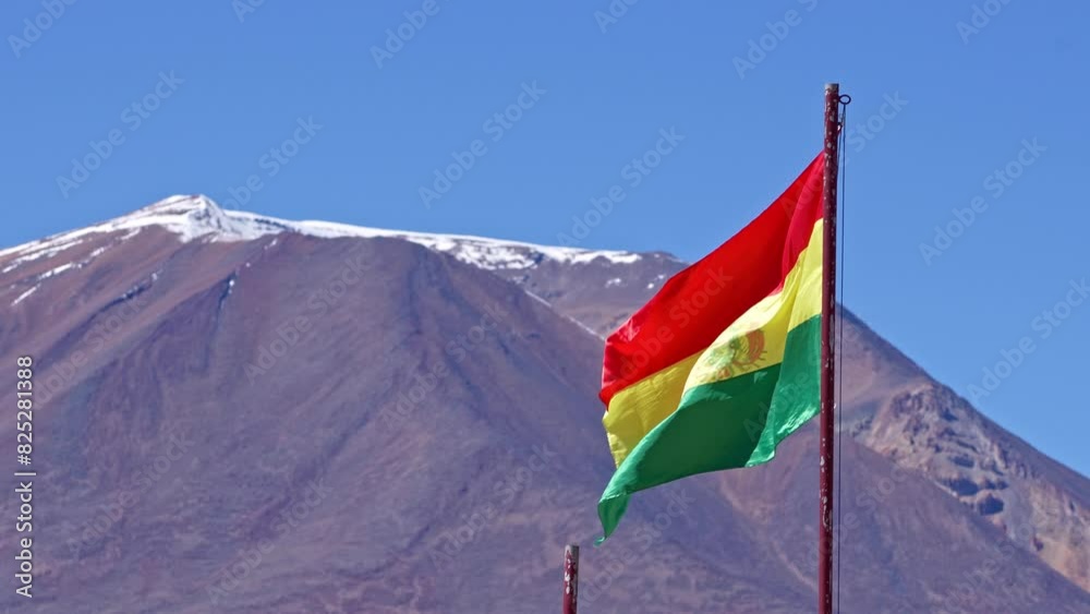 Bolivia Flag waves in wind swaying with snow capped mountain peak behind