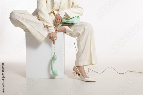 Model in fashionable clothes poses with vintage rotary telephone photo