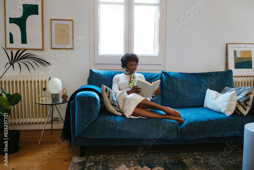 Relaxed woman reading a book on blue couch photo
