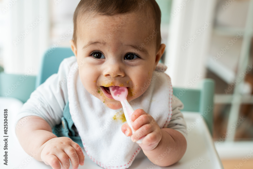 Adorable infant with food on face during feeding time Adorable infant with food on face during feeding time