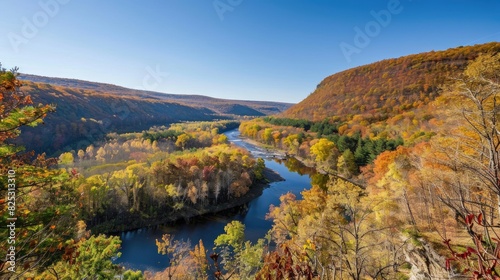 Valley landscape featuring forests and river with hill on right in autumn under clear blue sky