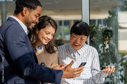 Happy businessman showing smart phone to colleagues  photo