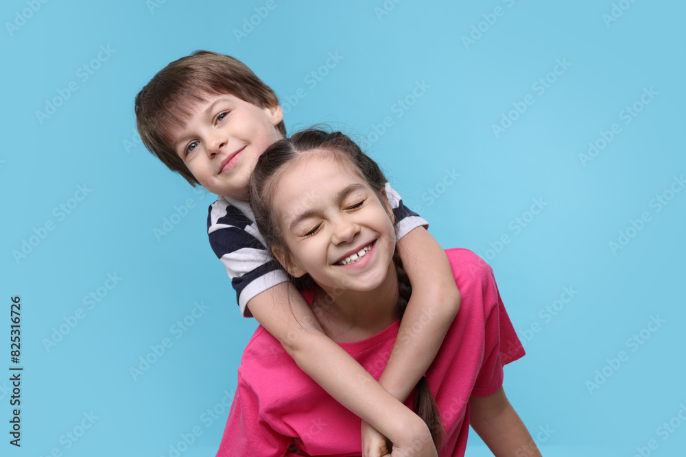 Happy brother and sister hugging on light blue background Happy brother and sister hugging on light blue background