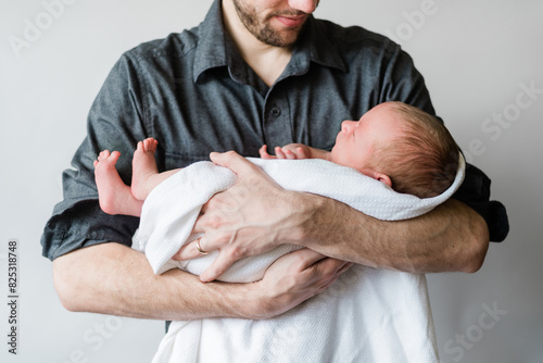 Father carefully holds his sleeping newborn