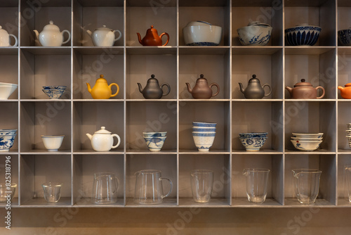 Ceramic tea pots with bowls and jugs on shelf