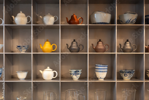 Ceramic tea pots with bowls and jugs on shelf photo