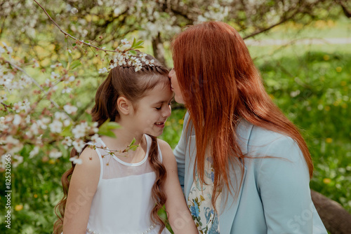 Mother and daughter in summer in a blooming garden