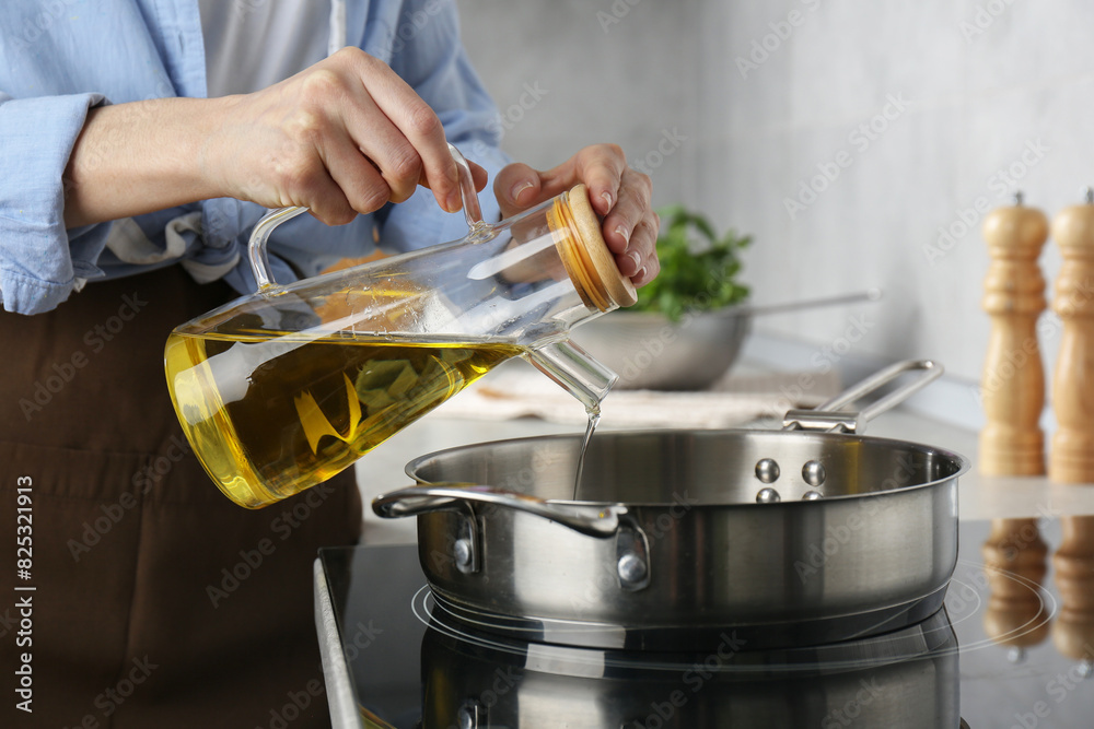 Vegetable fats. Woman pouring cooking oil into frying pan on stove in kitchen, closeup Vegetable fats. Woman pouring cooking oil into frying pan on stove in kitchen, closeup