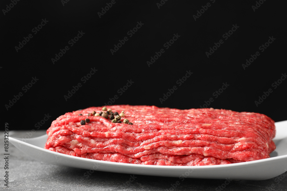 Raw ground meat and peppercorns on grey table, closeup Raw ground meat and peppercorns on grey table, closeup