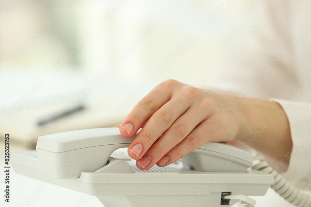 Assistant taking telephone handset at white table, closeup