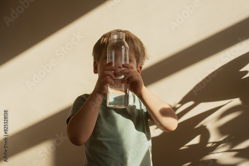 Child hides her face behind a bottle photo