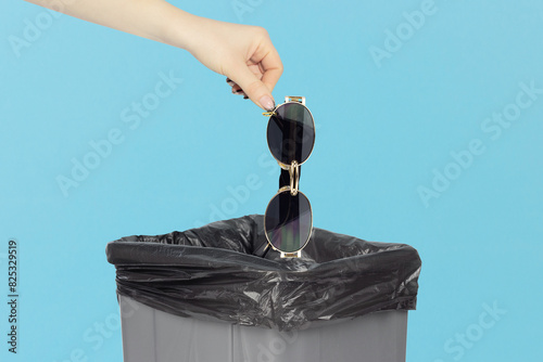 throw the women's sunglasses into the trash, outstretched hand with sunglasses in front of the trash can
