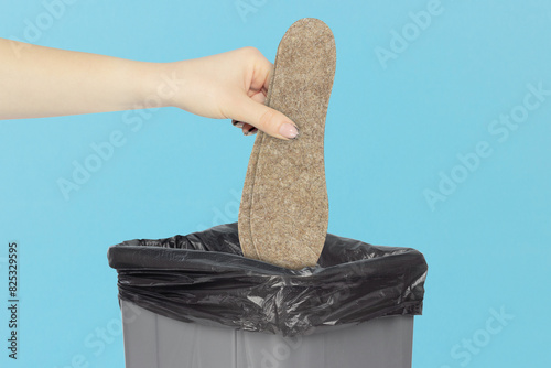 throw felt insoles for shoes in the trash, outstretched hand with felt insoles  in front of trash can photo