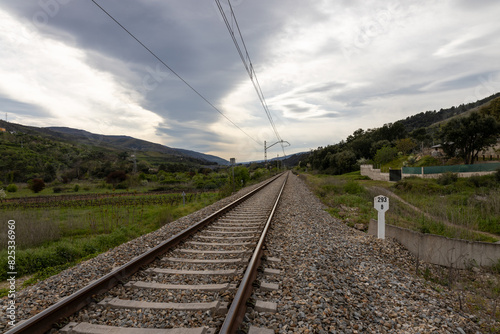 Railway track crossing green fields and mountains