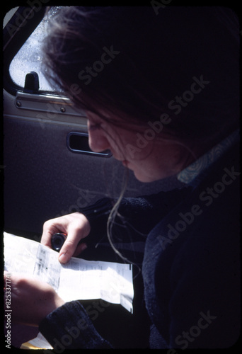 70's Old analog photo. Young woman reading instructions inside car photo