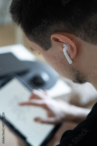 man using tablet with wireless headphones photo