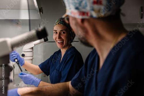 Smiling female biologist engaging in laboratory work with colleague
