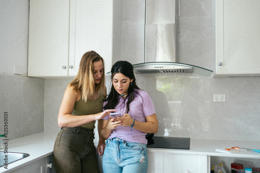 Women using smartphone in the kitchen at home Women using smartphone in the kitchen at home