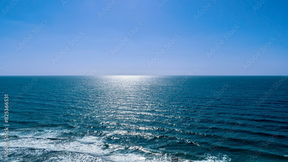 Scenic view of the sun shining over ocean waves reaching shore