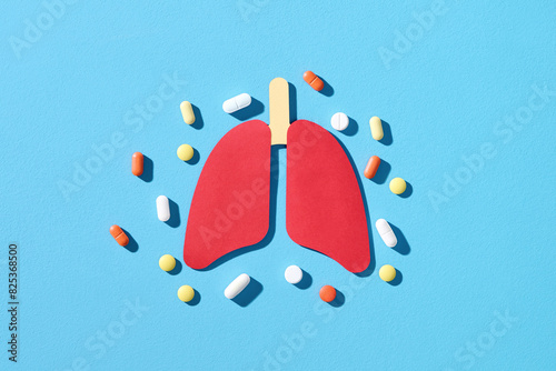 Lungs paper decorative model with pills on blue background photo