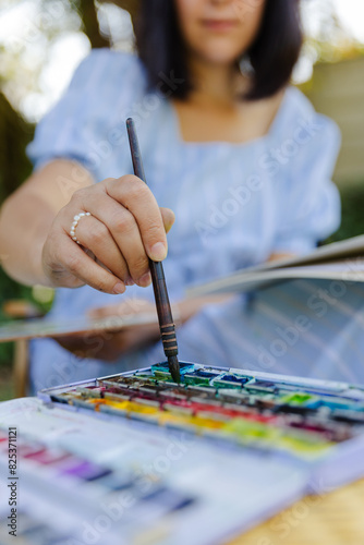 Crop blurred woman dipping brush in paint photo