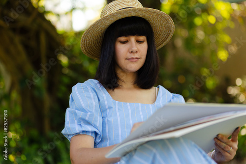 Happy woman artist painting on white sheets in park photo