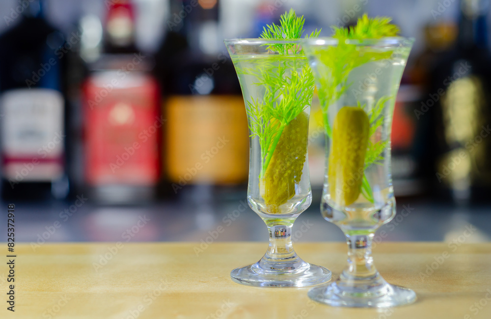 Shaken vodka and pickle juice with ice in a shot glass and garnished with small pickled cucumber and dill Shaken vodka and pickle juice with ice in a shot glass and garnished with small pickled cucumber and dill