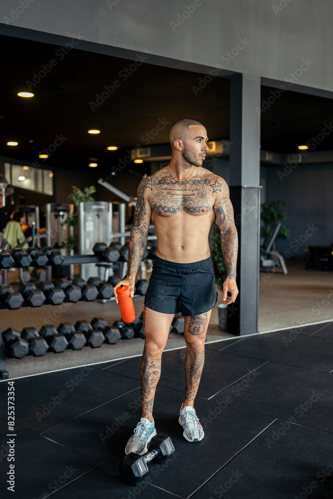 Young, tattooed male with a fit physique poses in a gym Young, tattooed male with a fit physique poses in a gym