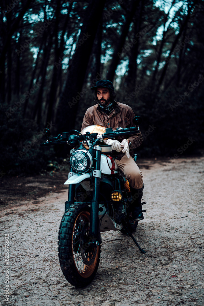 Vertical shot of a man on a motorcycle parked in a forest Vertical shot of a man on a motorcycle parked in a forest