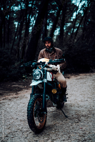 Vertical shot of a man on a motorcycle parked in a forest