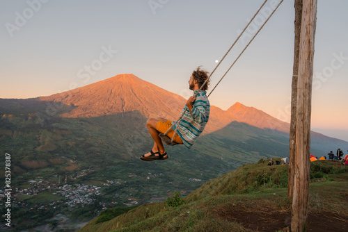 Man on a swing on the background of volcano on Lombok island  photo