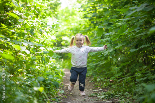 Portrait of smiling girl runs on the trail in the deciduous forest. Waving hands. Forest on bright light background.